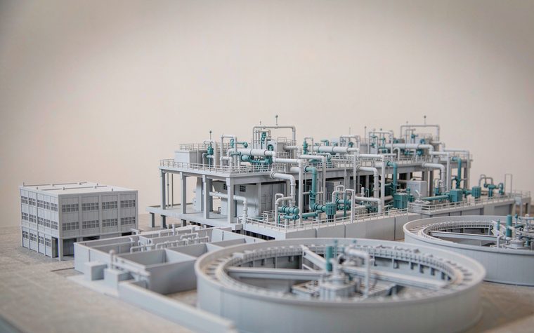 A scale model of a wastewater treatment facility with clarifier tanks and pipework
